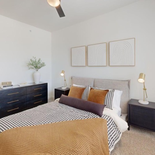 Model bedroom with low queen size bed with cushion headboard, side table and dresser